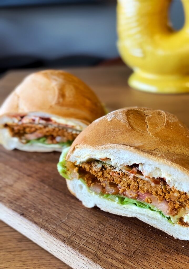 Panino con cotoletta vegana di fagioli cannellini, insalata, pomodoro, cetriolini, maionese e ketchup